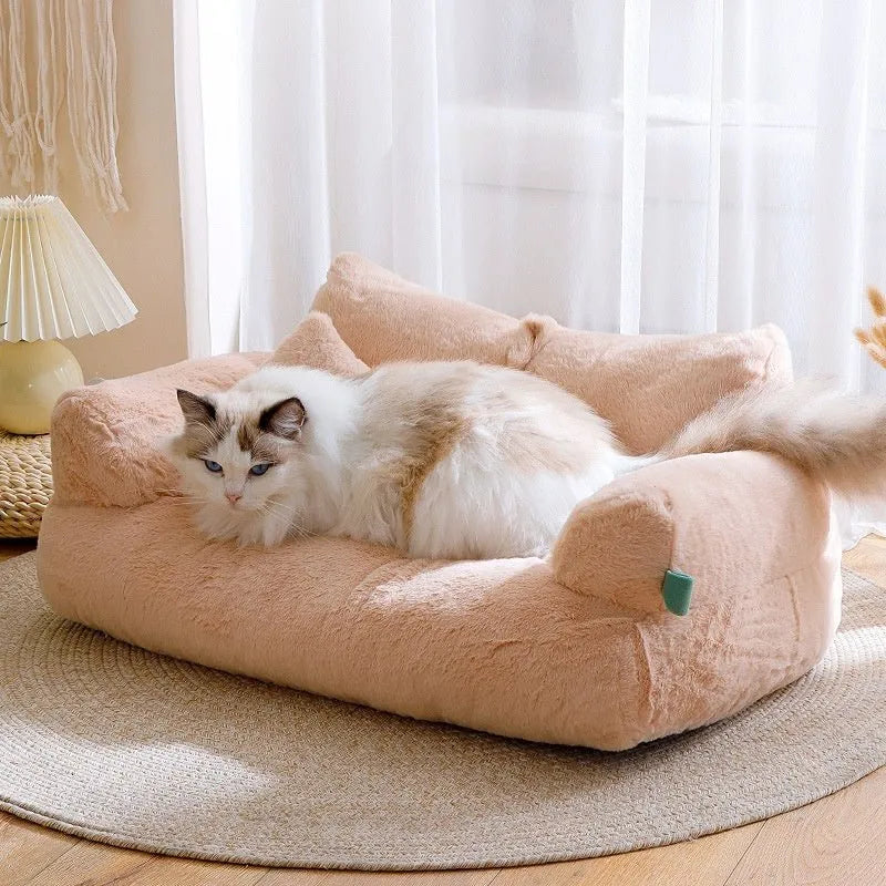 Cat lying on a fluffy pink pet bed in a bright room with white curtains.